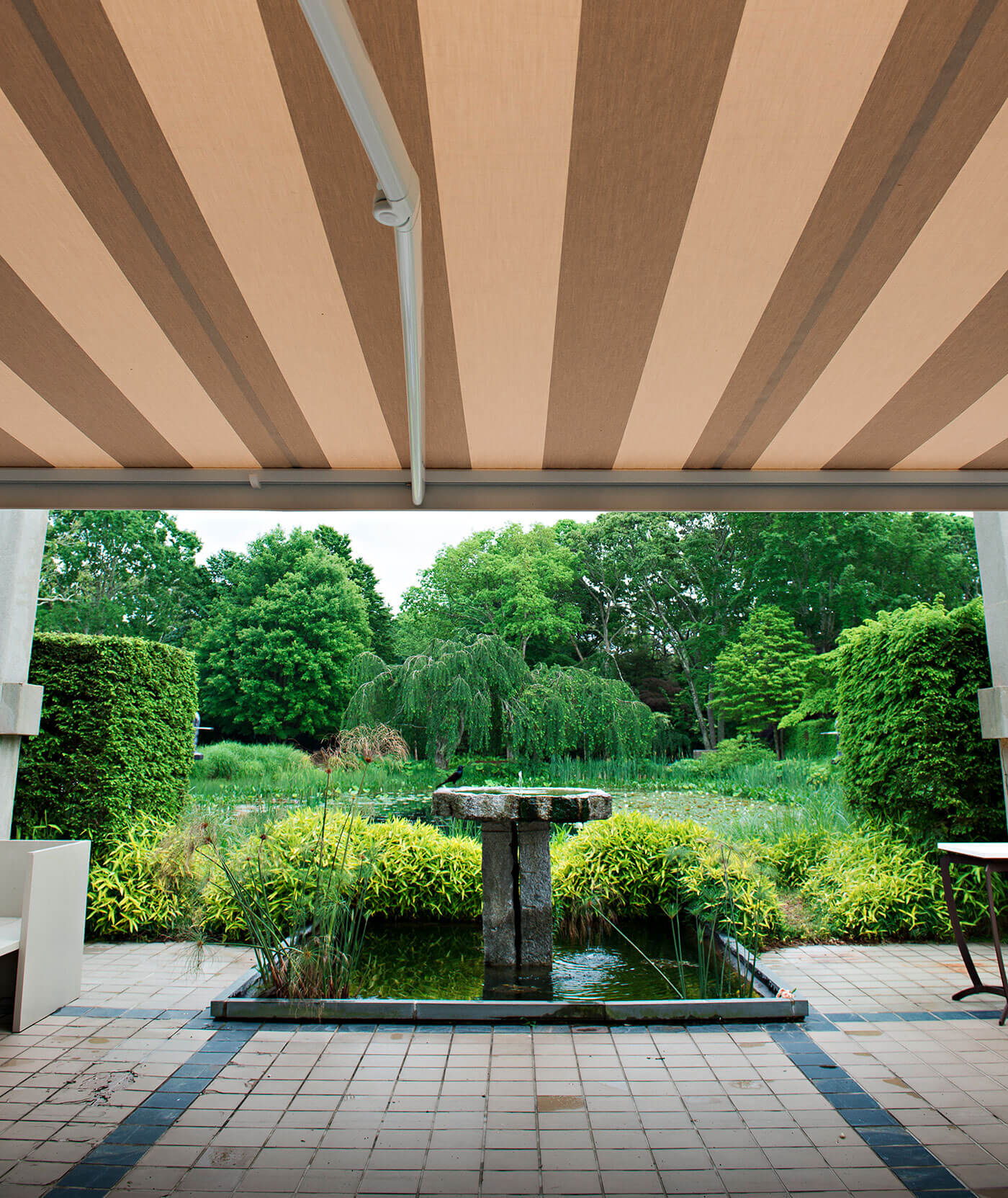Outdoor Garden shaded by retractable awning with striped beige Sunbrella fabric