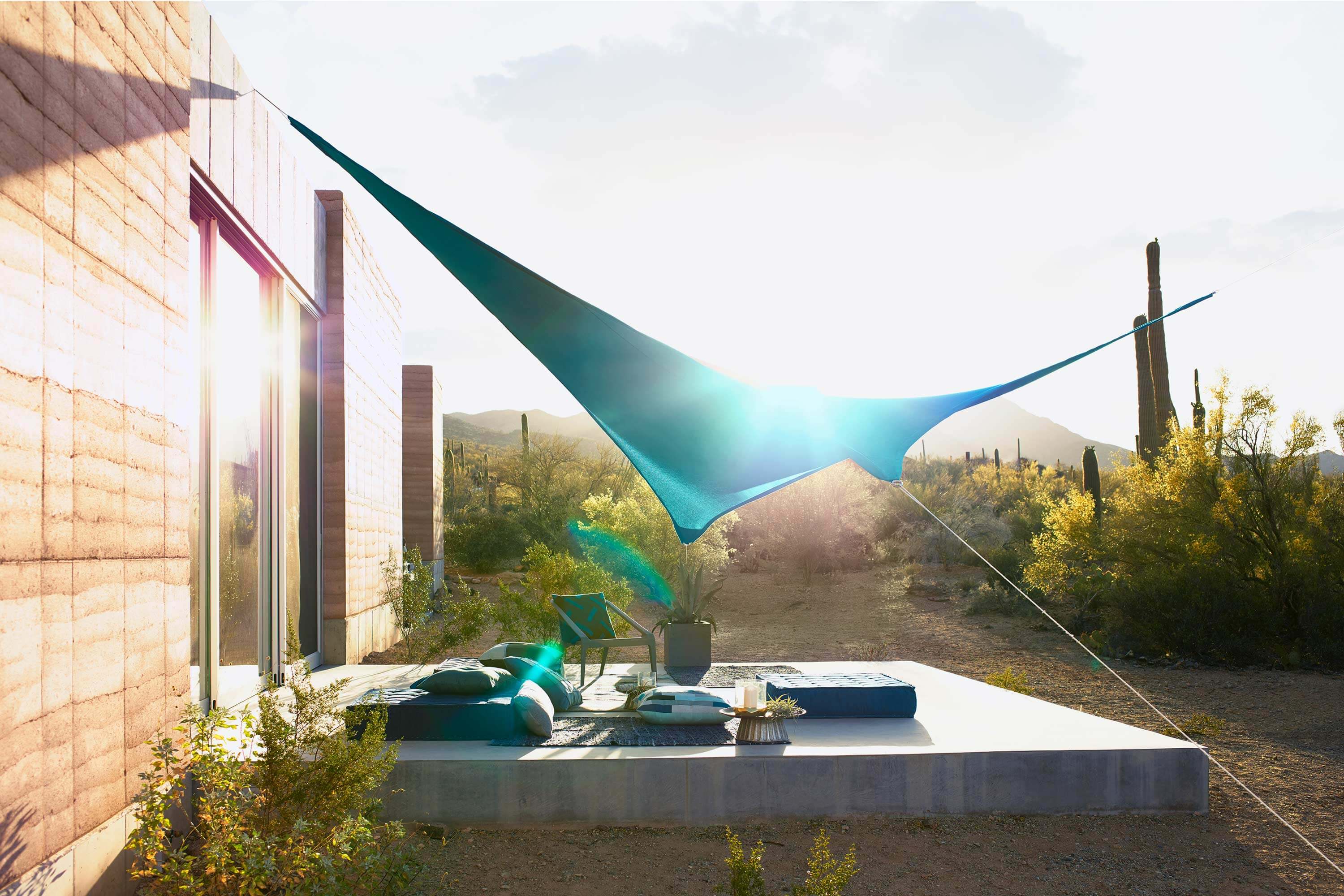 Outdoor patio in the desert covered with shade sail made using teal Sunbrella Contour fabric