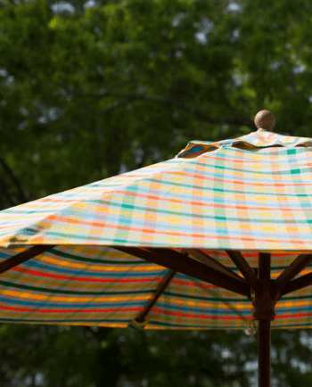A market umbrella with a bright plaid fabric from the Sunbrella Shift collection