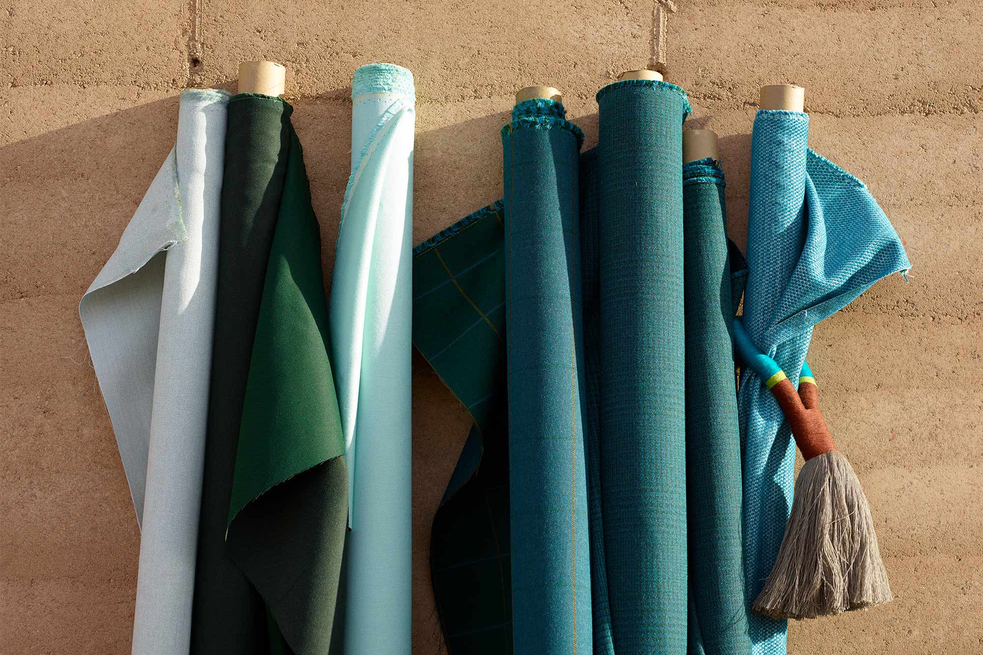 Rolls of teal Sunbrella upholstery fabrics against outside wall