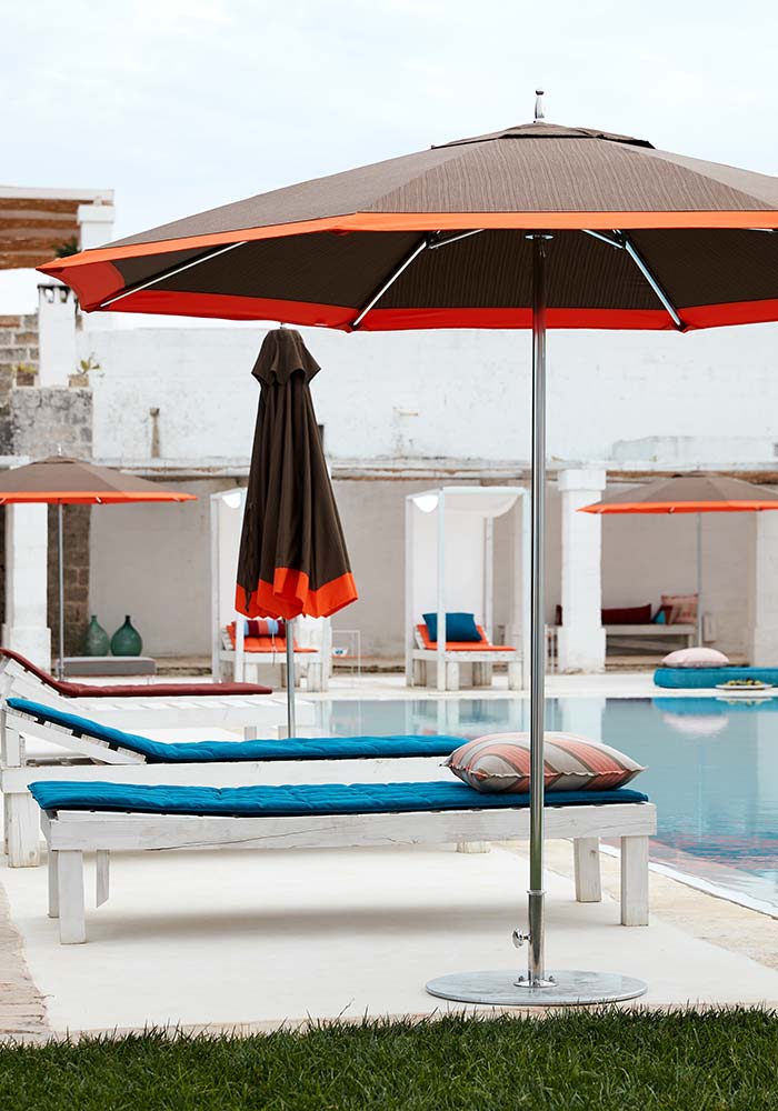 Brown umbrellas with orange trim, lounge seating, poolside.